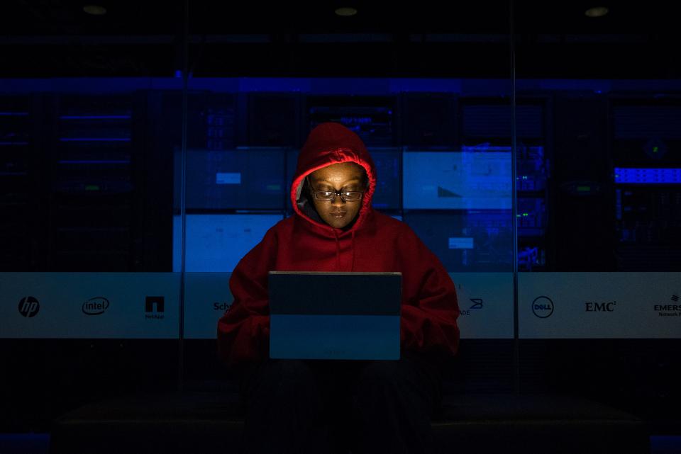 Person in a hood at a computer in a dark room