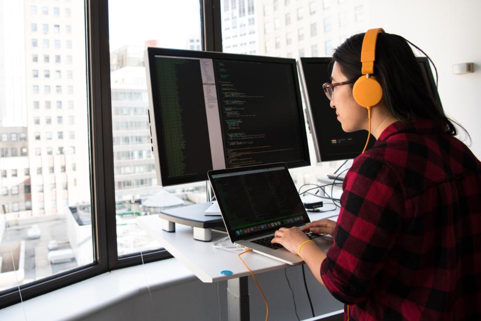 Engineer with headphones working at multiple screens